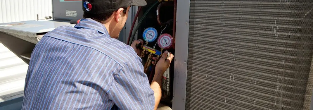 HVAC technician servicing a condenser unit in Paris